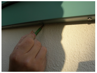 close up hand marking wall with pencil underneath shutter