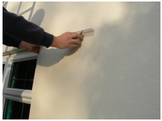 hands holding a hidden bracket in position on wall of house