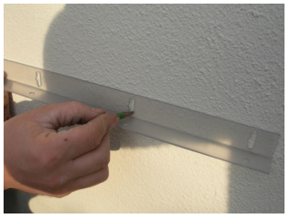 close up hand marking wall on house where bracket is to be fitted