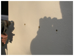 holes being drilled into wall of house