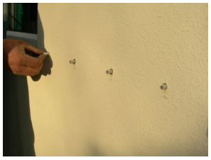 screws being fitted into pre drilled holes on wall of house