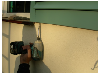 close up of drill attaching hidden bracket to bottom of shutter with screws