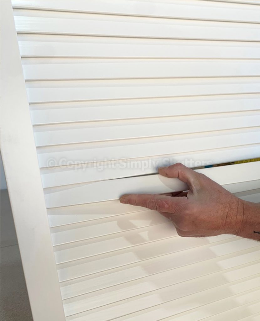 hand pressing louvre blade into place on door