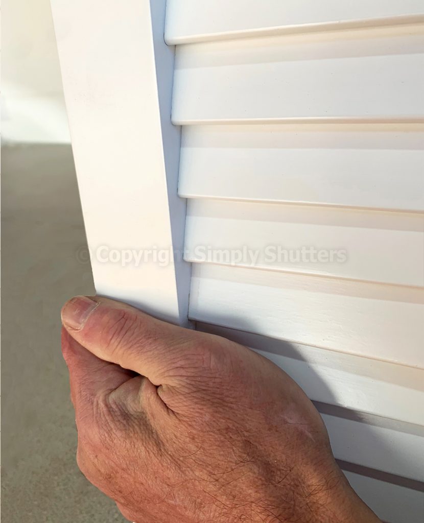 hand holding side of stile on white louvre door 