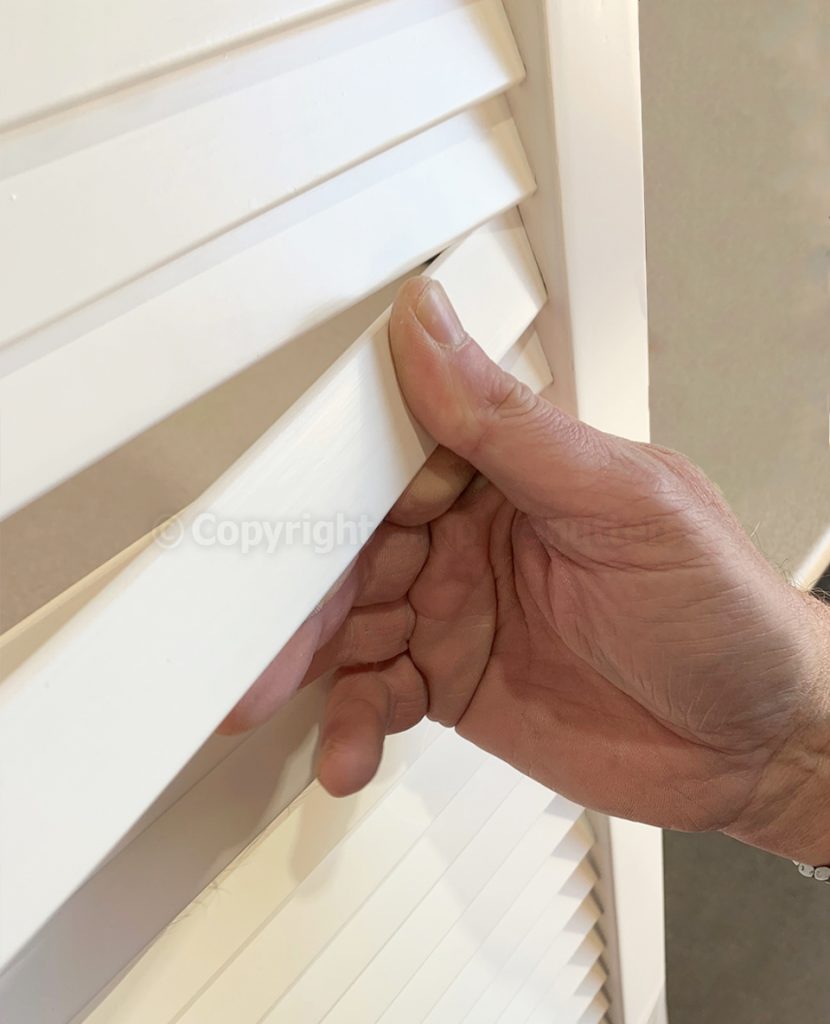 Thumb pressing a louvre blade into place on door 