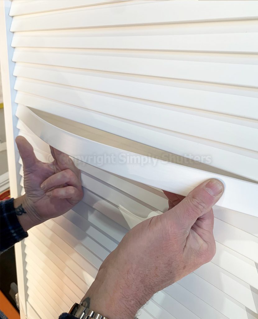 Hands bending louvre blade into place on door 