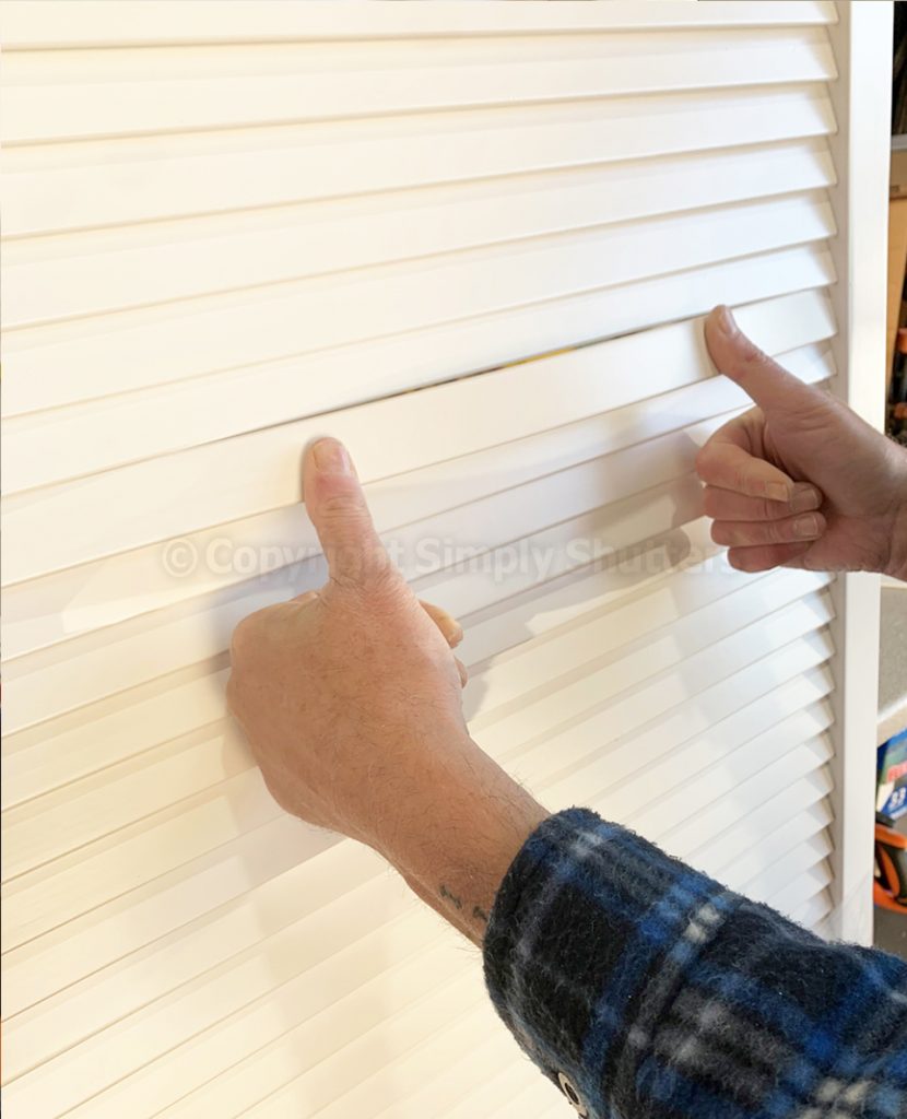 Hands pressing louvre blade into place on door 