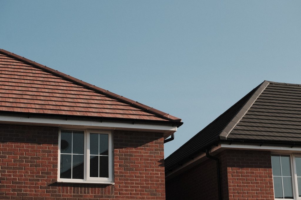 Top of roof of house showing closed window on first floor. 