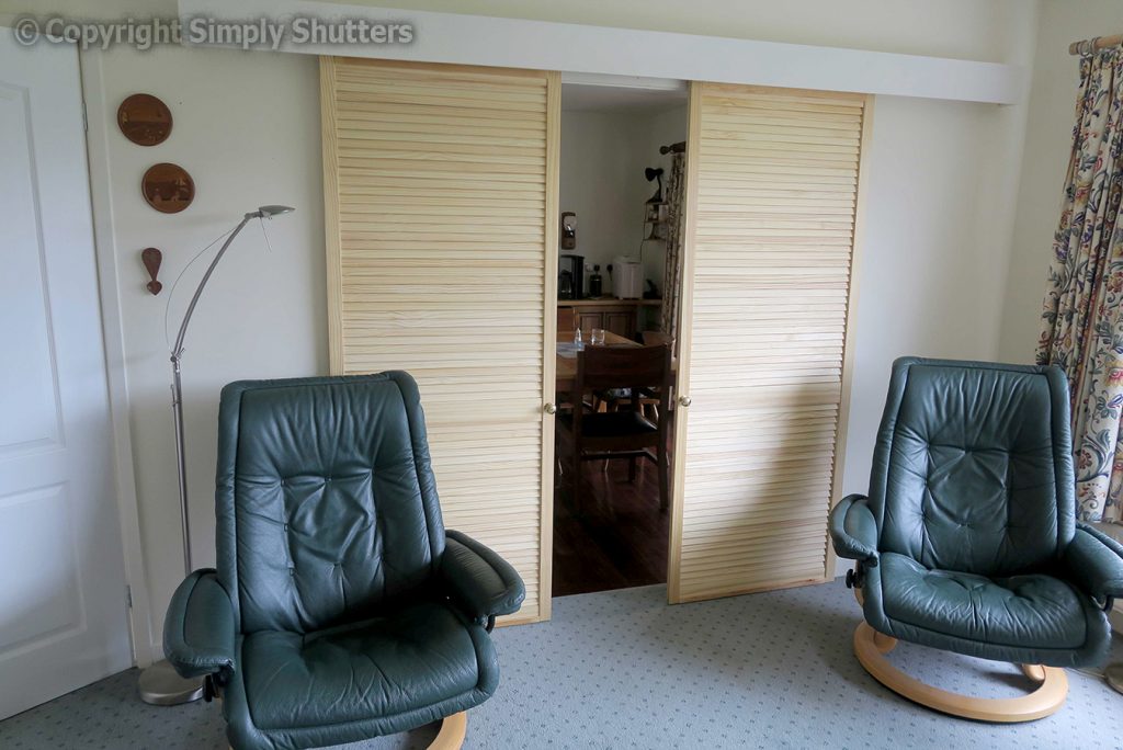 Louvre doors on slider behind 2 leather arm chairs 