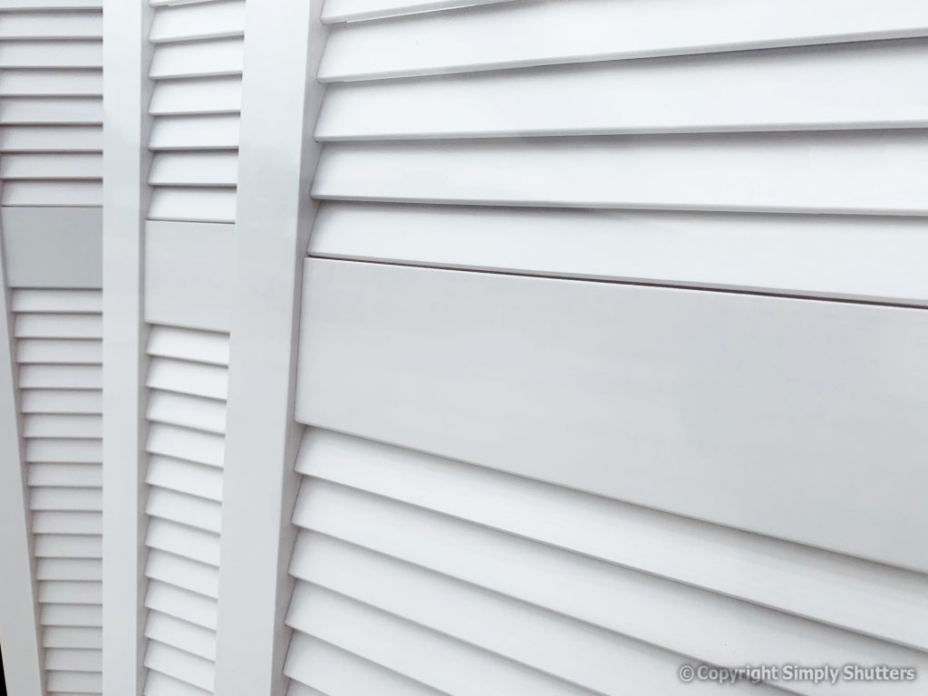 Close up white painted louvre doors with horizontal bar 