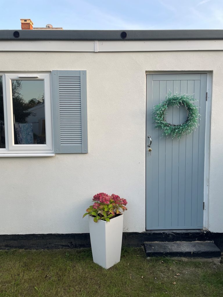 Grey door with reef, flower pot and installed grey shutter